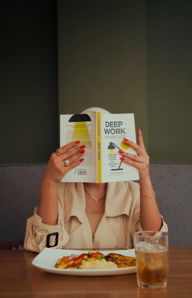 A woman sitting at a table reading a book